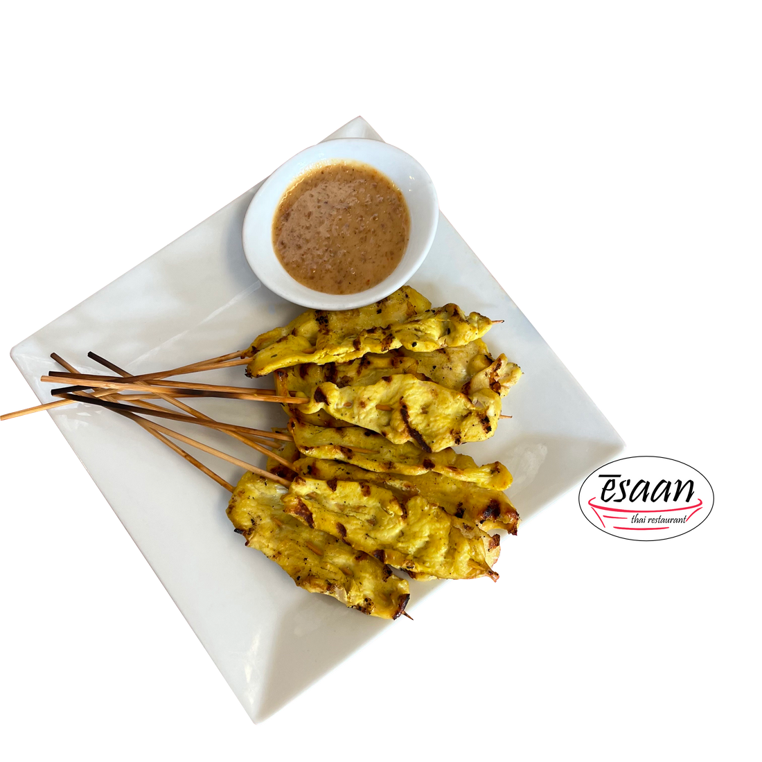 Grilled chicken skewered on bamboo next to a small bowl of peanut sauce